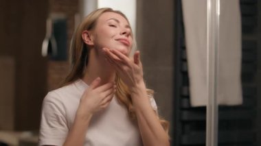 Enseye losyon kremi süren beyaz bir kadın model banyoda yaşlı güzellik karşıtı cilt bakımını nemlendiriyor. Ev banyosunda cilt masajına dokunan sağlıklı kadın derisini nemlendiriyor.