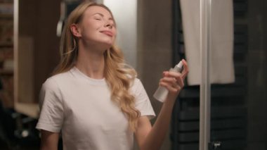 Mutlu Kafkasyalı kadın makyaj spreyi sıkıyor. Makyaj spreyi sıkıyor. Su toneri sıkıyor. Genç kız, cilt bakımı yapıyor.