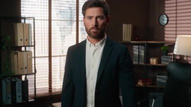 Ciddi, kendinden emin, 40 'lı yaşlarda, beyaz, orta yaşlı bir işadamı. Kendine güvenen bir iş adamı. Makamında çalışan ve kameraya bakan bir iş adamı.