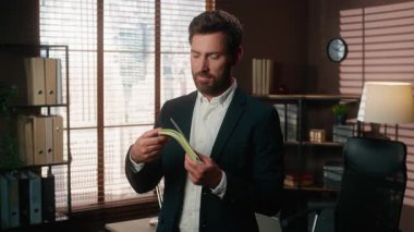 Kafkasyalı orta yaşlı iş adamı elinde para tutarak para kokluyor mutlu mesut sevinç verici iş mali başarısı ofis finansmanında gülümsüyor işveren dolarlar kazanıyor