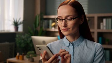 İş kadını, işveren, kadın müdür, ofisteki cep telefonu internet, akıllı telefon bağımlısı, mesaj yazan Kafkasyalı kız, internet üzerinden alışveriş uygulaması kullanarak sohbet cep telefonu kullanıyor.