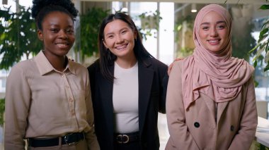 Çok ırklı, neşeli, güler yüzlü iş kadınları üç farklı etnik arkadaş kız öğrenciler Asyalı, Müslüman iş kadınları ofis bayan iş arkadaşları, kadın iş arkadaşları, kadın ortaklık pozu veriyorlar.