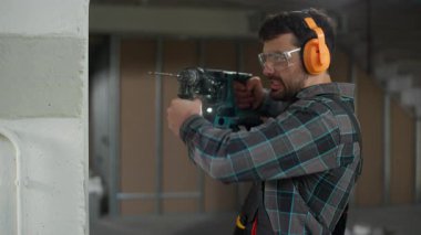 Tamirci beyaz adam çekiç onarım onarım inşaat inşaat mühendisi inşaat mühendisi ustabaşı elektrikli alet delici tutan bir işçiyle duvar deliyor.