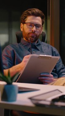 Kafkasyalı iş adamı tüccar işadamı analist gece ofis evraklarında evrak hazırlıyor. Fazla mesai yapıyor. İnternetten alışveriş yapıyor.