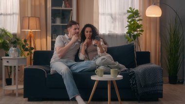 Gülümseyen çok ırklı çift, erkek, erkek, erkek, İspanyol kadın, kadın, cep telefonu alışverişi yapan, iç mobilya siparişlerini evde tartışan, akıllı telefon.
