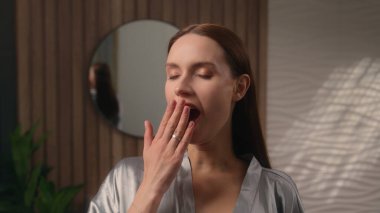 Kameraya gülümseyen beyaz kadın uykulu uykulu uykulu uykulu uykulu uykusuzluk uykusundan uyanıyor. Uykudan sonra esniyor.