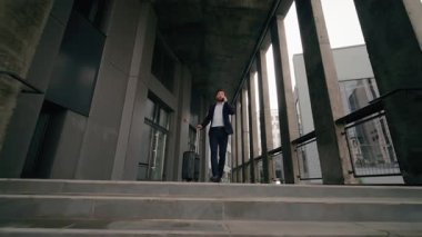 Stresli Kafkasyalı orta yaşlı iş adamı acele şehir içinde uçmak için havalimanında bavul taşıyan cep telefonuyla konuşuyor iş adamı seyahat sorunu gecikmeli uçak sorunu