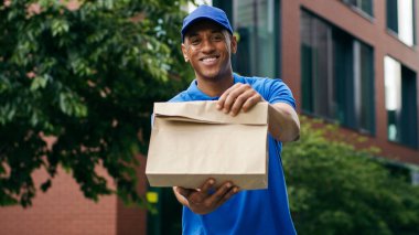 Portre mutlu bir şekilde gülümsüyor. Afro-Amerikan kuryeye bakıyor. Erkek yemek teslimatçısı.