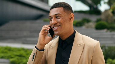 Mutlu gülümseyen Afro-Amerikan erkek girişimci işveren müdürü işveren iş adamı şehir işadamı arkadaş canlısı konuşan cep telefonu akıllı telefon konuşmaları konuşma