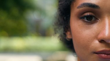 Yarım portre kırpılmış görünümlü Afro-Amerikan iş kadını kameraya bakıyor ciddi bir koyu tenli iş kadını sağlık hekimi kadın feminizm kadın görme yeteneği olan kadın şehirde yakın mesafede.