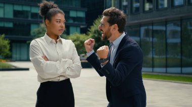 İki çok ırklı iş arkadaşı şehirdeki farklı duygular Afrika kökenli Amerikalı kadın iş kadını hayal kırıklığına uğramış Kafkasyalı erkek işadamı kazananı zafer için bağırıyor.