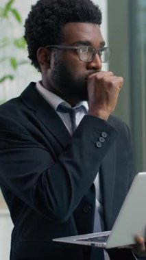 Dikey görüş Afro-Amerikalı düşünceli endişeli iş adamı dizüstü bilgisayarla sohbet ediyor iş yazma sorunu çözmesi zor iş adamı pencereden dışarı bakan etnik erkek işadamı