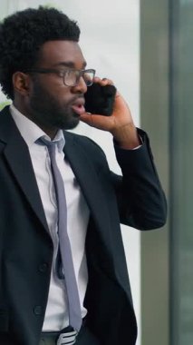 Dikey bakış kızgın kızgın kızgın kızgın Afrikalı Amerikalı iş adamı konuşuyor cep telefonu sorunu tartışılıyor ofiste öfkeli iş adamı tartışması pencereden bakan erkek adam tartışması