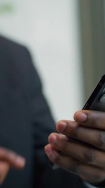 Dikey görüş, Afrika kökenli Amerikalı iş adamının elinde akıllı telefon numarası var. Konuşan kızgın etnik işadamı, şirket çağrısını vurguladı.