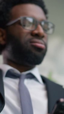 Dikey bakış, Afrikalı Amerikalı iş adamının cep telefonuyla konuşması, kötü haber sorunu, akıllı telefon, internet mesajı işadamı, boyun ağrısı, baş ağrısı, yorgun erkek sorunu.