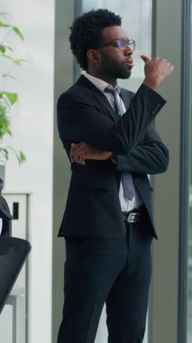 Dikey görüş dalgın Afrikalı Amerikalı iş adamı pencereden dışarı bakarak çözüm üretiyor erkek iş adamı profesyonel düşünce zor düşüncelere karar veriyor strateji üzerinde kafa yoruyor