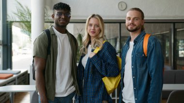 Portre Üniversite Akademisi birlikte eğitim görüyor. Üç öğrenci çok ırklı arkadaşlıklar kuruyor. Erkek, beyaz, Afrikalı, Amerikalı erkek, kadın, kameraya bakıyor.