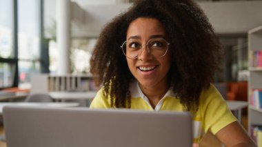 Afro-Amerikan mutlu kız öğrenci internetten bilgisayar okuyarak sınavı geçiyor. İyi sonuç fırsatı. Üniversitede iş kadını olarak zafer kazan.