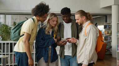 Üniversite koleji öğrencisi dört öğrenci erkek çok ırklı erkek Kafkas Afrikalı Amerikalı kadın kız cep telefonu bağımlısı alet kullanarak komik videolar seyrediyor eğlenceli eğlence uygulaması