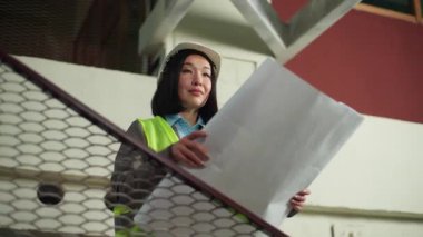 Koreli Çinli iş kadını elinde planlarla gülümseyen iş kadını Japon Asyalı kadın inşaat planı projesi inşaatçı mutlu mimar kız mimar patron inşaat mühendisi