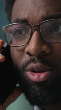 Yüzü kapatın, profesyonel Afro-Amerikan işadamı cep telefonundan konuşan, danışman, müşteri danışmanı, iş adamı ofisindeki monitör bilgisayarına bakan adam.