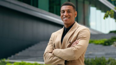 Kendine güvenen çapraz el ele tutuşmuş silah gülümsemesi mutlu Afrikalı Amerikalı erkek girişimci kameraman iş adamı emlakçı emlakçı şehir işadamı ofis binasındaki emlakçıya bakıyor