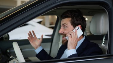 Kafkasyalı mutlu adam cep telefonundan konuşuyor akıllı telefon zafer iş adamı arabası duygusal şoför iş konuşmasını kutluyor alıcı otomobil başarısı müşterisi içeride.