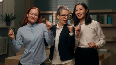 Dans eden mutlu çok kültürlü takım kadınları zaferi kutluyor. Finansal başarı, iş dünyası, iş kadınları, iş adamları, çok ırklı kadın işverenler, iş arkadaşları ofisleri.