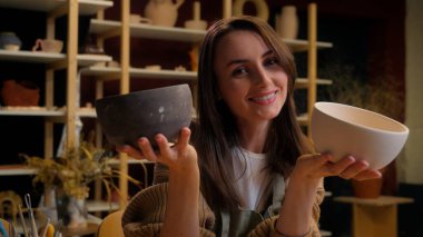 Bir çömlek atölyesinde, bir kadın iki güzel kaseyi ustalıkla elinde tutuyor, eşsiz bir sofra takımı yapma tutkusunu sergiliyor.