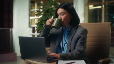Mutlu Asyalı Koreli iş kadını iş kadını bilgisayarla çalışıyor. İnternette yazı yazıyor. İş adamı, internet yöneticisi, kahve içiyor.