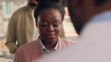 Eczaneden müşterileri satın alan Afrikalı kadın gülümseyen ilaç satın alan eczacı adam Cleint 'e ilaç siparişinde yardımcı oluyor.