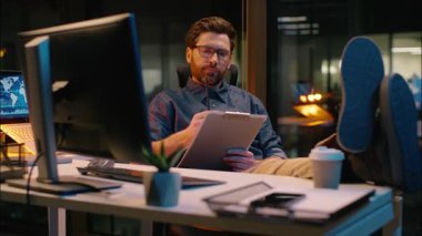 Kafkasyalı iş adamı tüccar işadamı analist gece ofis evraklarında evrak hazırlıyor. Fazla mesai yapıyor. İnternetten alışveriş yapıyor.