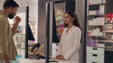 Eczane sağlık sorunundaki erkek müşteri, eczacı kadın öksürük şurubu tedavisine yardım ediyor eczane ilaçlarını satın alıyor, ilaç satışı için ilaç tedavisi görüyor.