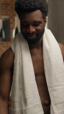 Afro-Amerikalı adam ev banyosunda bir bardak su içiyor. Rutin sabah susuzluğu çeken, gülümseyen, soğuk su içen, ferahlatıcı alışkanlık. H2O ferahlatıcı, taze sağlık suyu vücudunu nemlendiriyor.