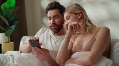 Yatak odasındaki başvuruları tartışan mutlu, beyaz bir çift. Dijital oyun oynayan cep telefonlu bir kadın. Çevrimiçi sabah yatağı kız arkadaşı alışverişi yapan bir erkek.