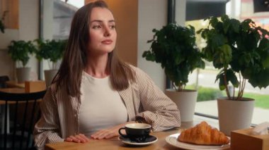 Kafe 'de beyaz kadın ziyaretçi kol saati ile geç saatte iş görüşmesi yapıyor. Bekliyor. Kafeterya masasında yalnız bir kadın var.