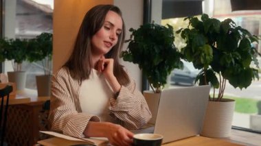 Kafede uzaktan kumandalı, kahve içen Kafkasyalı iş kadını dizüstü bilgisayar keyfi, içecek molası, iş bitirme, kafeterya masasında çalışan serbest çalışan kadın iş kadını.