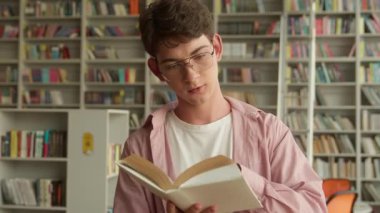 Kafkasyalı erkek öğrenciyi kapatın. Şiir okuyan ergen öğrenci. Kitap kitabı okuyor. Kütüphane eğitiminin sayfasını çeviriyor.