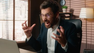 Öfkeli Avrupalı iş adamı, dizüstü bilgisayar hatası ile çalışırken ofisteki internet hatasında aşırı çalışan erkek girişimci iş adamının öfkesine bağırıyor.