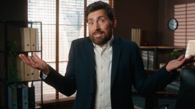 Ofisteki portre, kafası karışmış Kafkasyalı iş adamı, erkek işveren şirket CEO 'su kamera karşısında omuz silkme, omuz silkme, tereddütlü omuz silkme. Yüksek