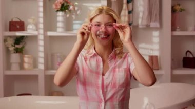 Beyaz kadın, pembe ev banyosunda mutlu bir şekilde gülümseyen, kameraya gülen, kalp şeklinde gözlük takan, gülen, uçan sabun köpüklerini kandırarak eğlenen, neşeli, neşeli, çekici bir kadın.