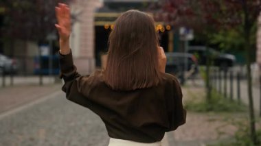 Arkaya bakan duygusal Kafkasyalı kadın şehir kızıyla konuşuyor, cep telefonuyla konuşuyor, iletişim kuruyor, sohbet ediyor sokak ortasında el kol hareketleri yaparak yürüyor.