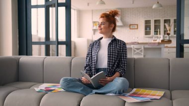 Gülümseyen mutlu rüyalar ev sahibi ev sahibi tasarım tasarımı renkli palet renkleri ev koltuğunda beyaz kadın kameraya gülümseyen notlar.