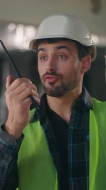 Kafkasyalı müteahhit telsizdeki telsizciyi işaret ediyor. İnşaatçı müteahhit erkek. Telsiz seti, teknik bağlantı mühendisi.