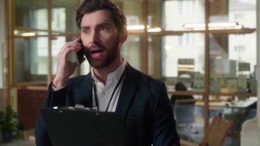 Sinirli iş adamı işvereni, ofisteki cep telefonuyla konuşan işadamını sinirlendirdi. Erkek yönetmen, orta yaşlı, sinirli, çılgın kavgacı, olumsuz diyalog sorununu tartıştı.