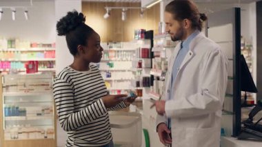 Eczane, eczacıya, eczacılık danışmanlığına yardım ediyor. Kadın, erkek, beyaz, erkek, kadın, eczanedeki Afrikalı erkek, ilaç alıyor.