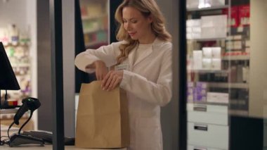 Eczane ilaç paketi kadın doktor ceket eczacı sağlık görevlisi ilaç sipariş hapları vitamin hapları kağıt torbada kadın beyaz kadın eczane asistanı