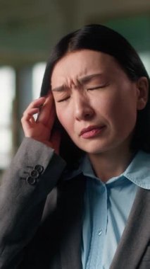 Asyalı iş kadını baş ağrısı çekiyor. Yorgun Çinli kız Koreli kadın çalışan yönetici ofiste çok çalışıyor. Baş şakaklarına masaj yapıyor.