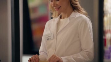 Eczanedeki gülümseyen kadın doktor eczacı ilaç satan, ilaç alan, hap alan, vitamin alan, kredi kartı siparişi veren eczane alışverişi yapan müşteriler.