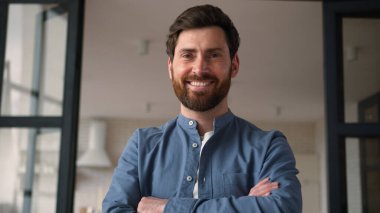 Kendinden emin beyaz bir ebeveyn mutlu yetişkin erkek portresi gülümsüyor orta yaşlı baba iş adamı baba ev içi ev sahibi çapraz silah sigortası kredisine kameraya bakıyor.